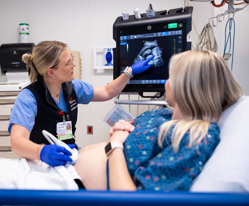 Resident performing ultrasound on pregnant patient