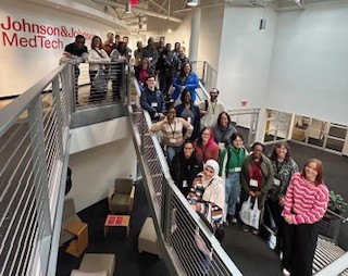 Large group of people posing on a staircase at Johnson and Johnson facility
