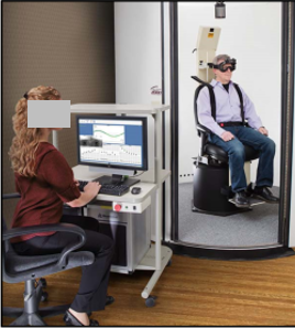A subject sitting in a Neuro-Otologic measurement chair and a technician viewing results on a nearby computer