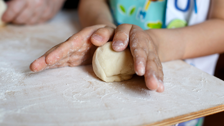 child hands rolling dough