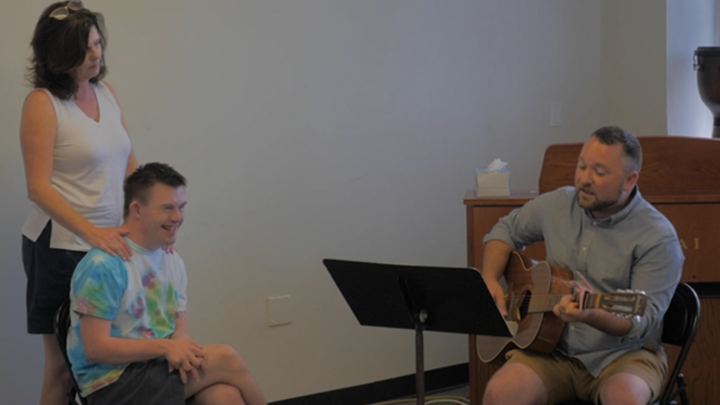 a person playing guitar with two people listening