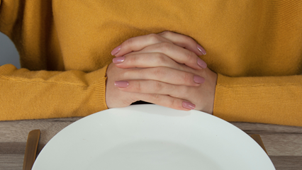 hands folded in front of plate
