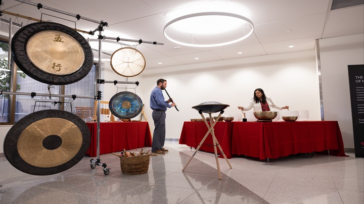 Two people performing sound immersion with gongs, sound bowls, and flutes