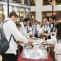 Students in white coats are served food
