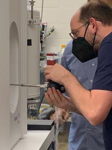  Image of a  trainee inserting a side-entry Cryo-holder (with a cryo-EM sample/grid) into the Talos L120C.