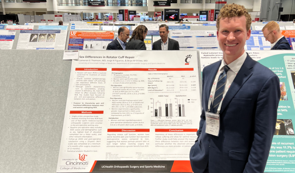 Image of  Cameron Thomson MD, 2021-2022Jorge Figueras BS, 2021-2022 Orthopaedic Research Fellow presenting podium and poster at AAOS 2022 in Chicago.