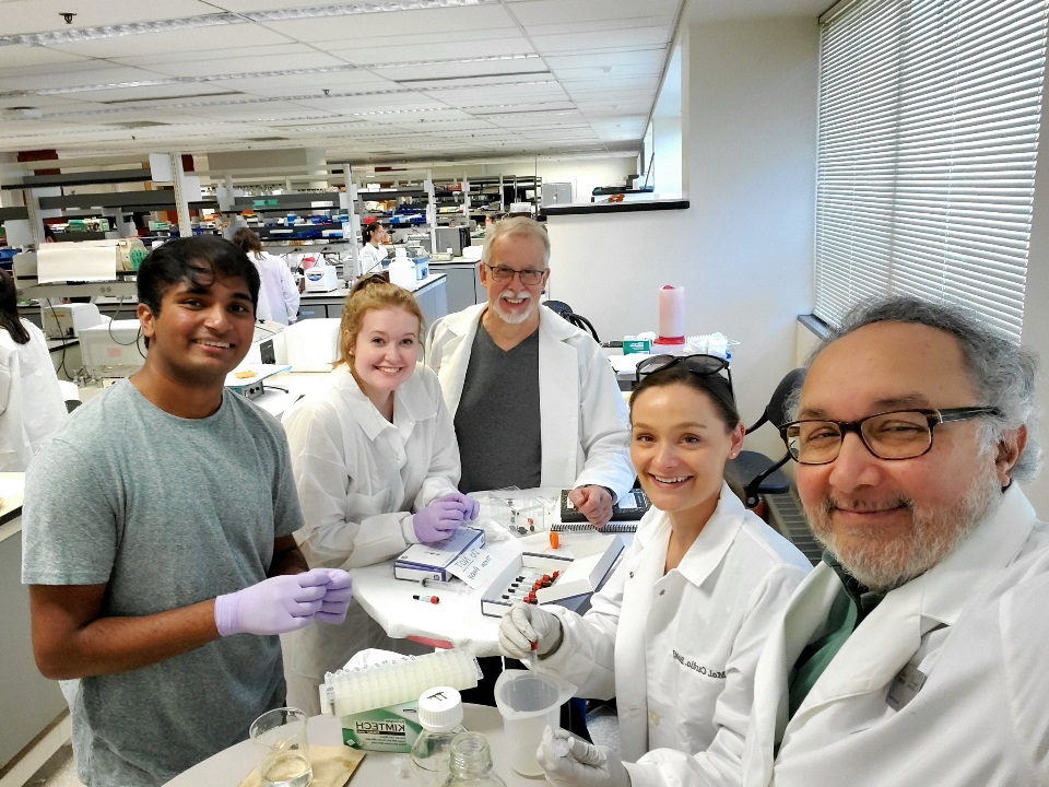 Image of Dr. Menon with students in a lab